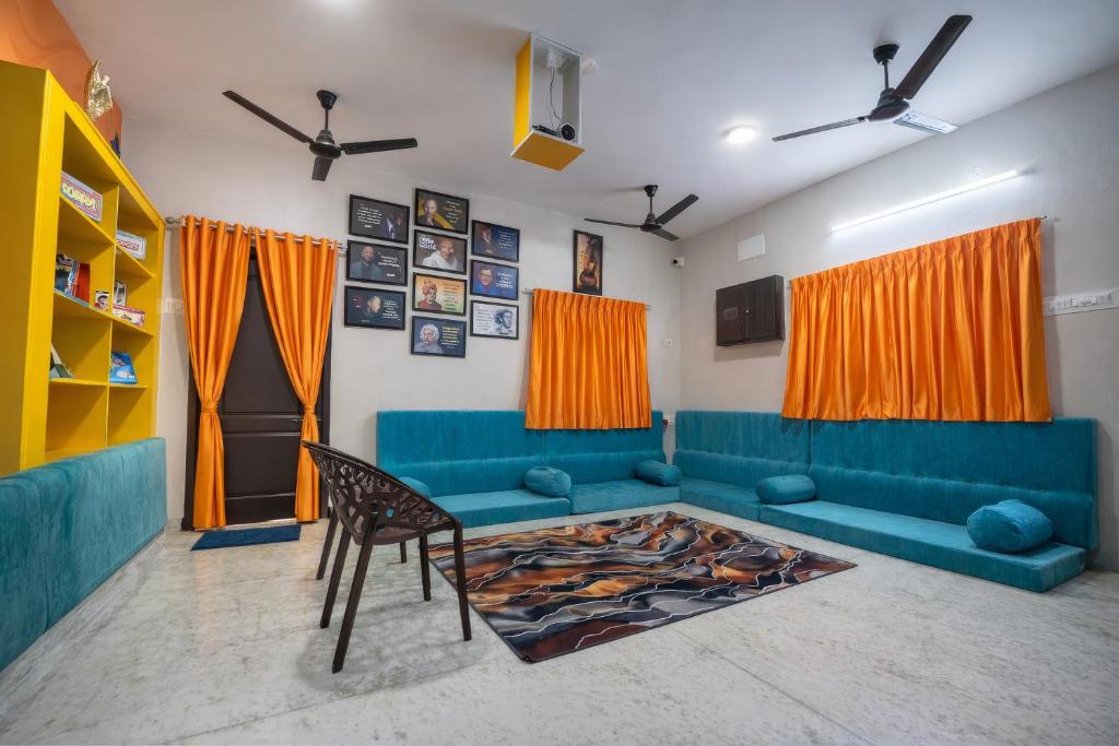 a living room with a blue couch and a chair at Rayzen Stays & Backpackers Hostel in Chennai