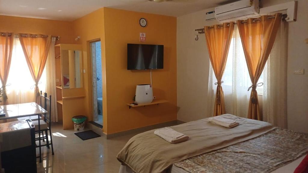 a bedroom with a bed and a tv on the wall at GLEN RESIDENCY in Chinchinim