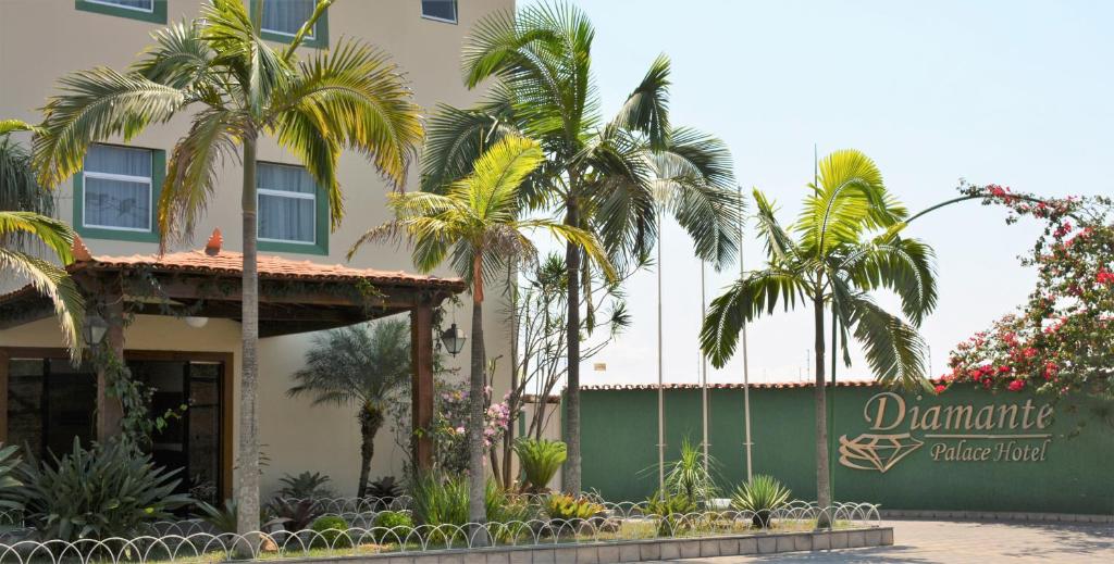 a hotel with palm trees in front of a building at Diamante Palace Hotel in Diamantina