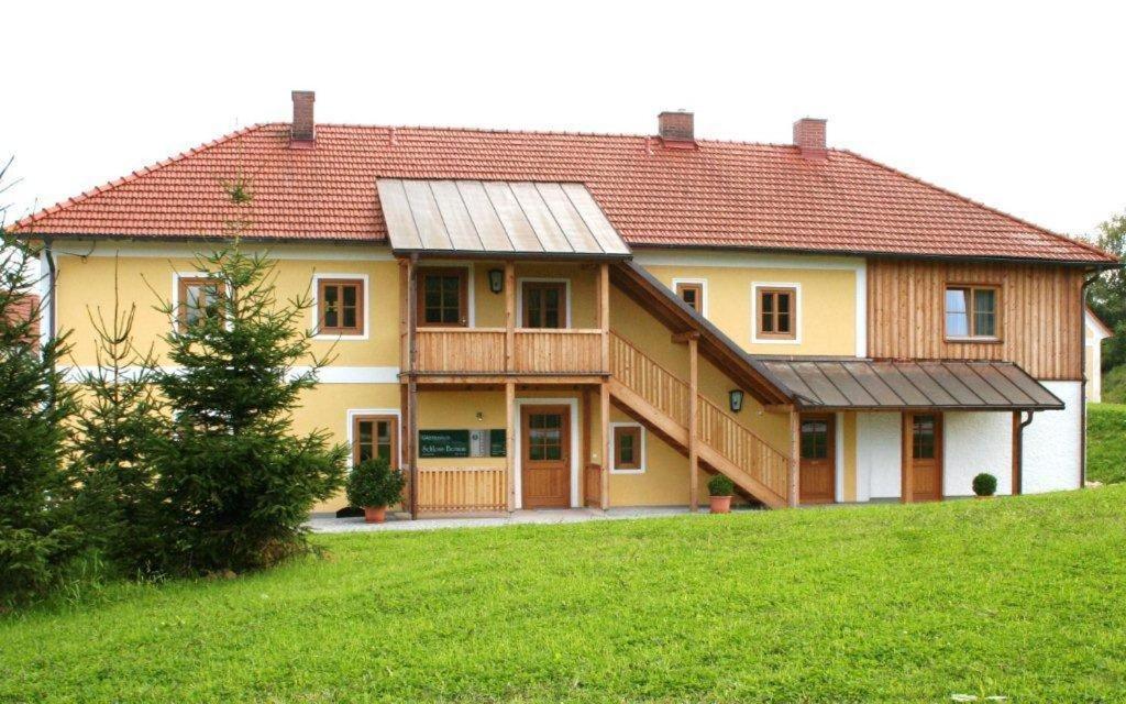 ein großes gelbes Haus mit rotem Dach in der Unterkunft Gästehaus Schloss Bernau in Fischlham