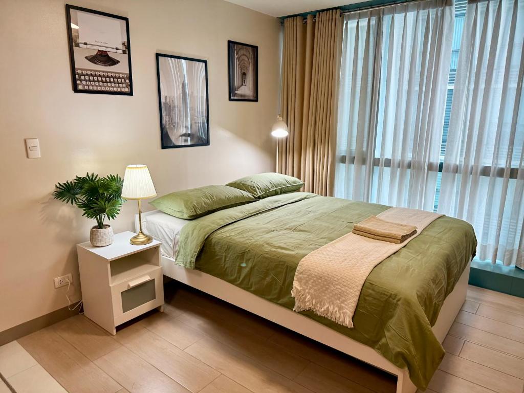 a bedroom with a large bed and a window at The Vibe BGC Uptown Apartment in Manila