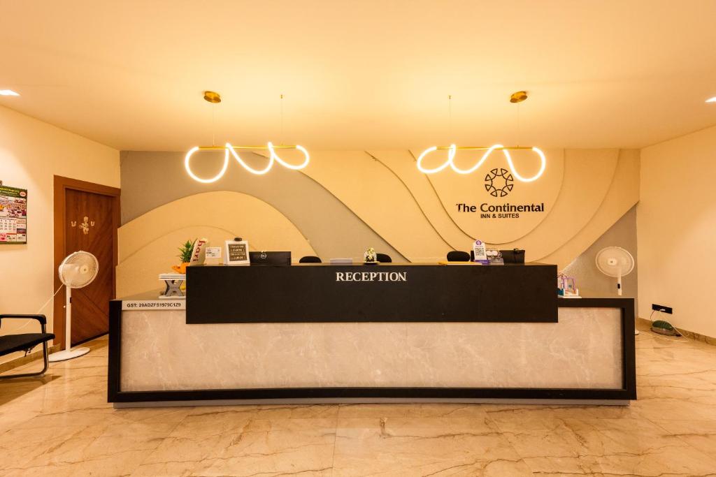 a reception desk in a lobby with a sign at THE CONTINENTAL INN & SUITES in Mysore