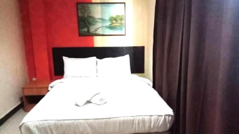 a bedroom with a white bed with a red wall at Hotel Wings Kuala Lumpur in Kuala Lumpur
