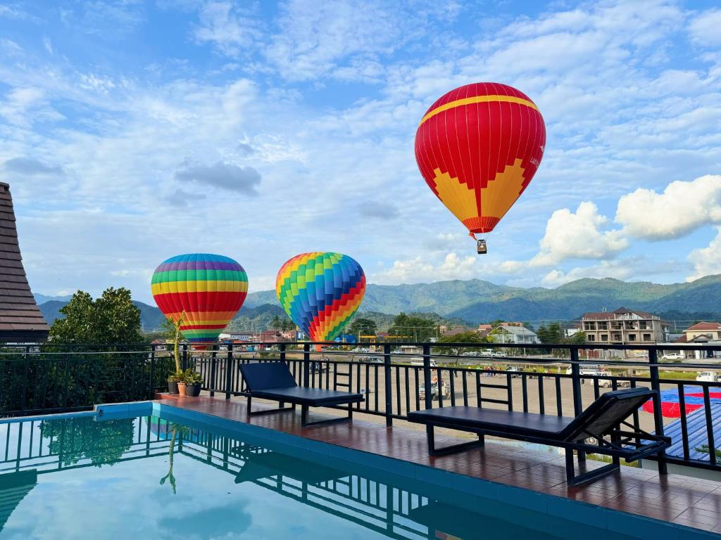 three hot air balloons flying over a swimming pool at Vang Vieng Sisavang Hotel in Vang Vieng