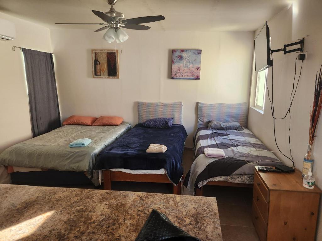 a room with two beds and a ceiling fan at Depa Jardines Anahuac in Mexicali