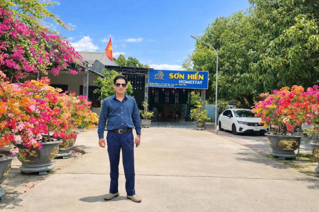 a man standing in front of a store with flowers at Sơn Hiển Homestay in Cam Lâm