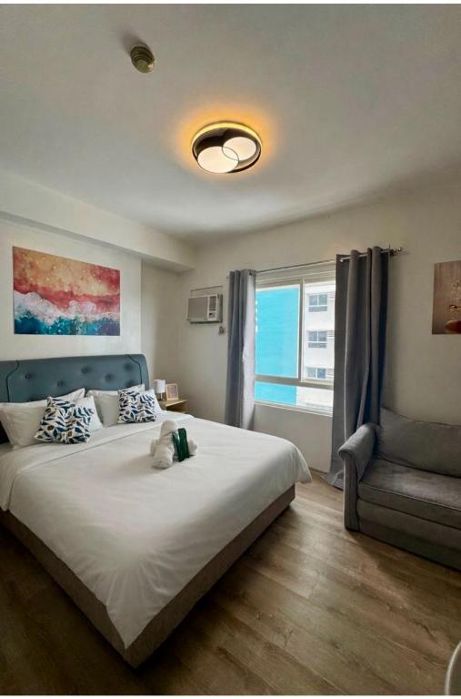 a bedroom with a large white bed and a chair at Sebby Studio in Bacolod