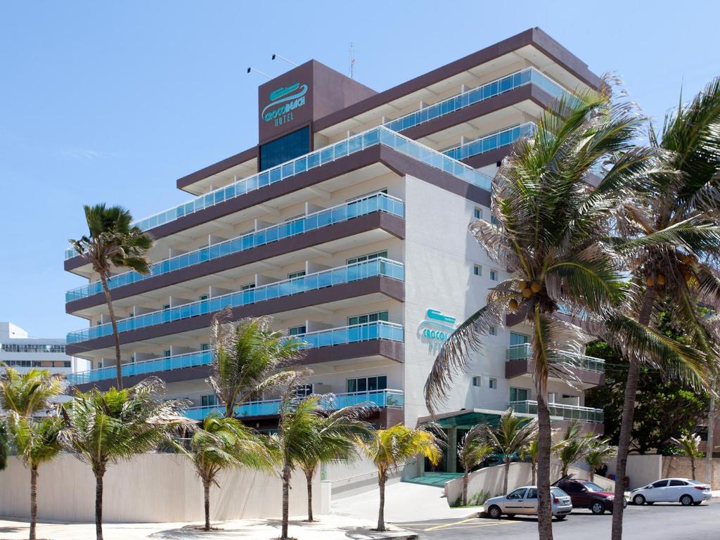 um edifício com palmeiras em frente em Crocobeach Hotel em Fortaleza