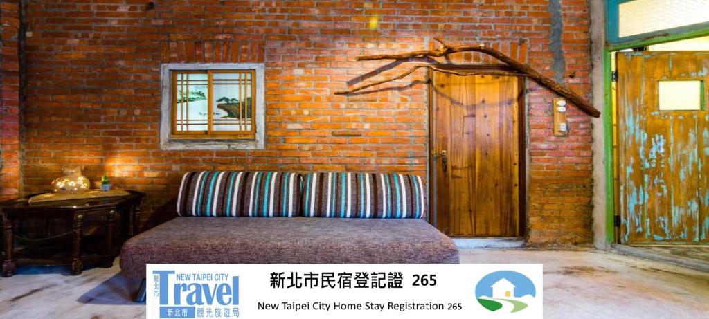 a room with a bed and a brick wall at Lungta BnB in Jiufen