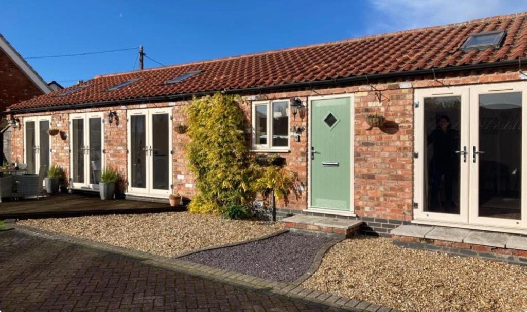 a brick house with a green door at The Stables in Metheringham
