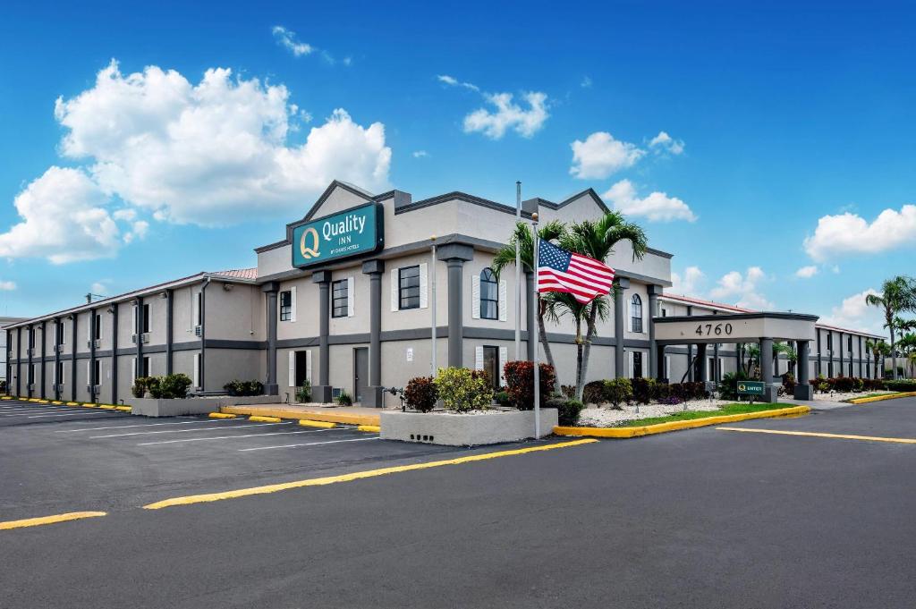 a hotel with an american flag in a parking lot at Quality Inn Fort Myers Cape Coral in Fort Myers