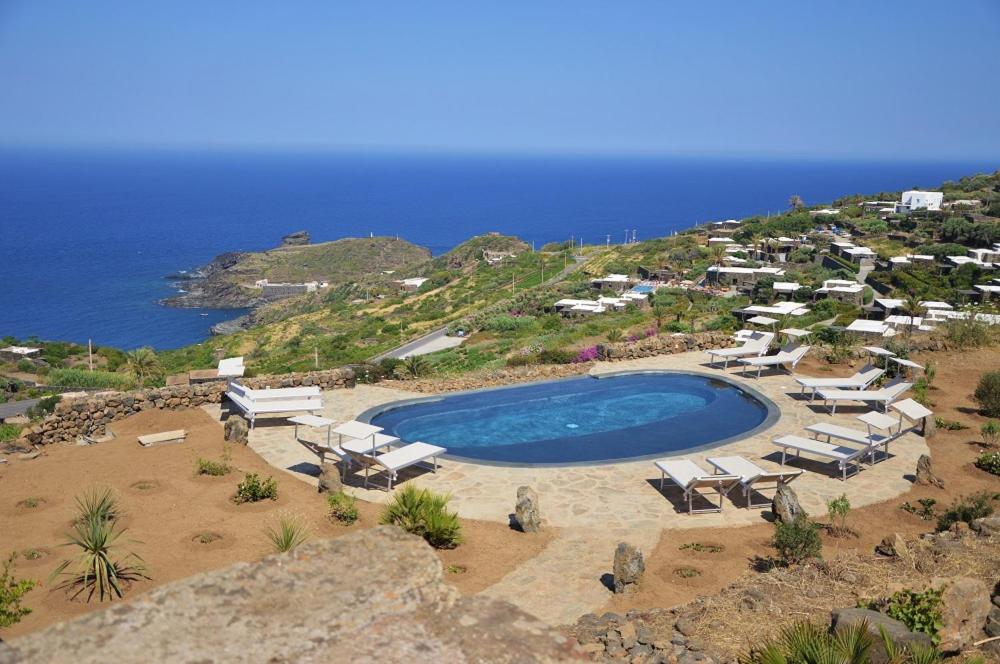an aerial view of a pool with chairs and the ocean at Dammuso La Ginestra in Pantelleria