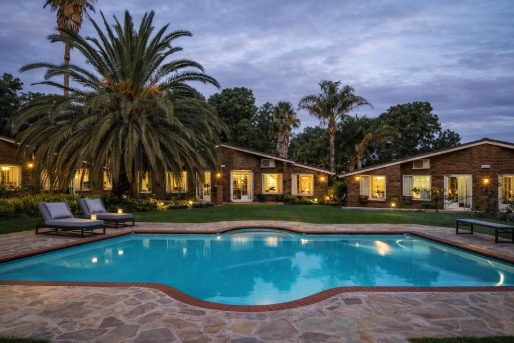 a swimming pool in front of a house with a palm tree at Newcastle Inn in Newcastle