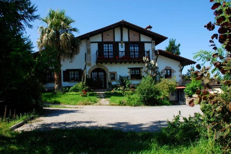 une grande maison blanche avec un palmier en face de celle-ci dans l'établissement Casa Rural Iketxe, à Fontarrabie