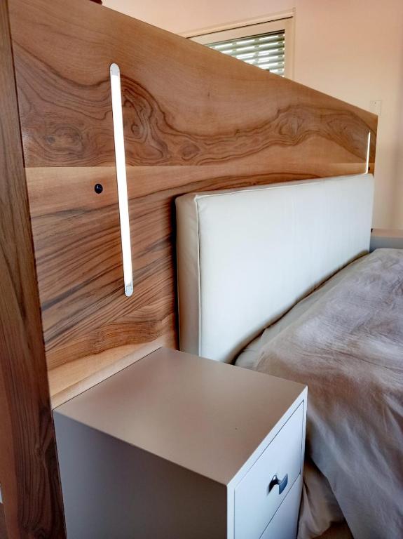 a bed with a wooden headboard and a white drawer at LE SITE in Specchia