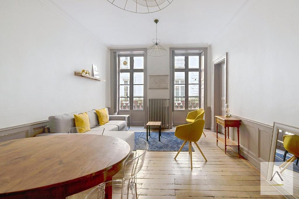 a living room with a table and yellow chairs at L'Historique in Rennes