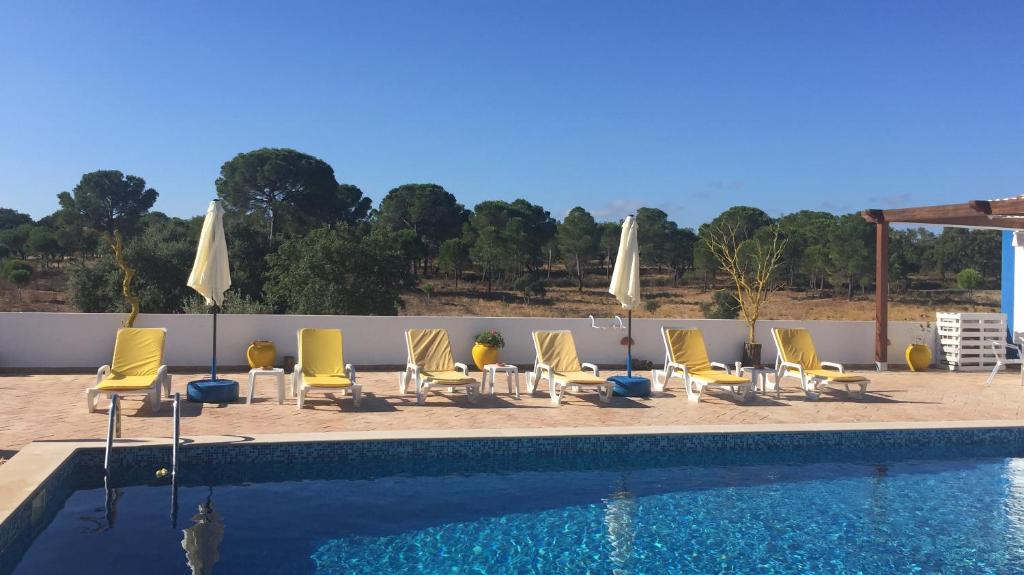 a group of chairs and umbrellas next to a swimming pool at Herdade Alem Santos in Lousal