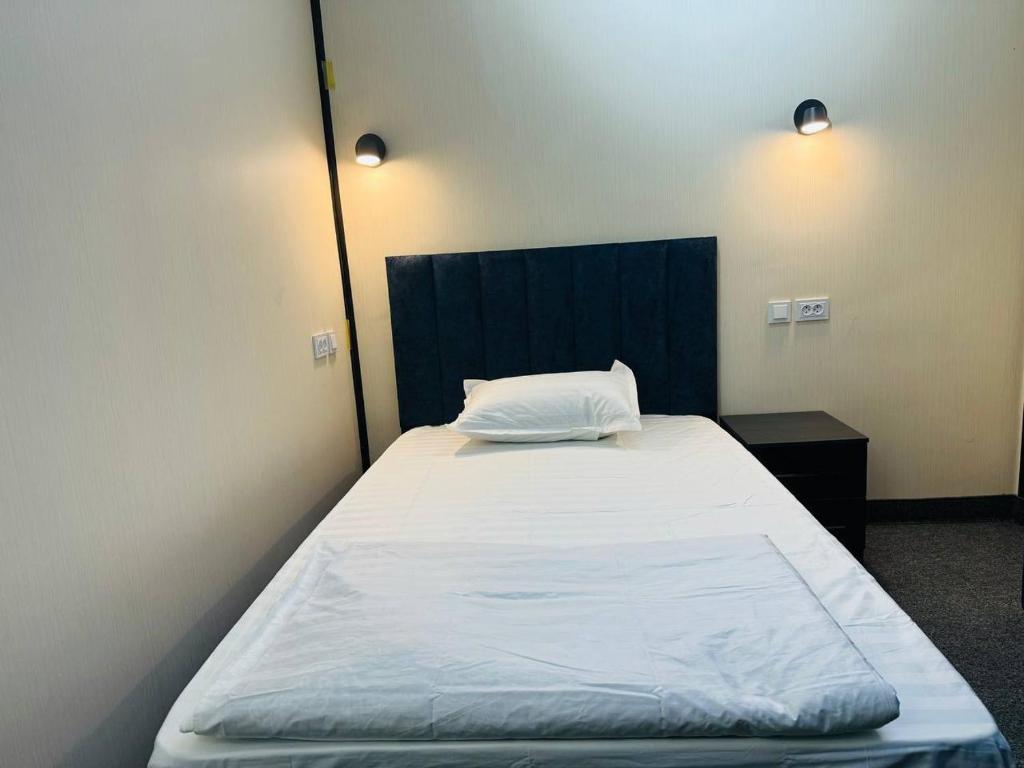 a bedroom with a large bed with a black headboard at TOPTEN Hotel Tashkent in Yalanghoch