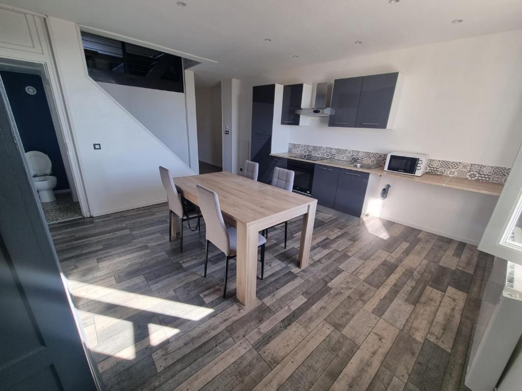 a kitchen with a wooden table and chairs at Le Duplex in Coligny