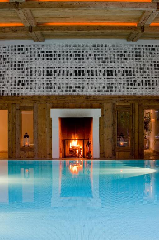 a large swimming pool in a building with a fireplace at Hotel Villa Irma in Merano