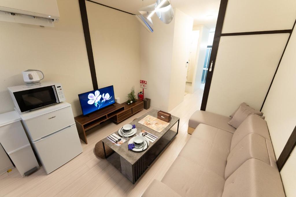 a living room with a couch and a tv at JPtrad 葵 なんばや心斎橋にも直結の8名様まで宿泊可能の広々メゾネット in Osaka