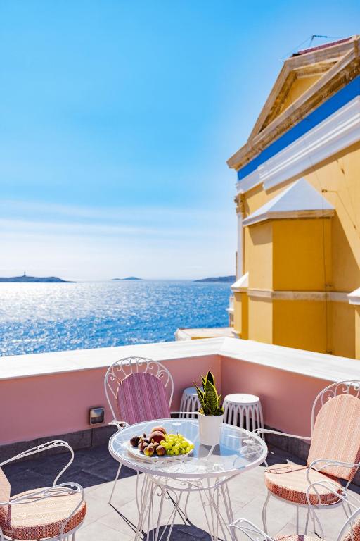 a table and chairs on a balcony overlooking the ocean at Villa Selena - 1830s Art-House Suites in Vaporia, 50m from Asteria Beach in Ermoupoli
