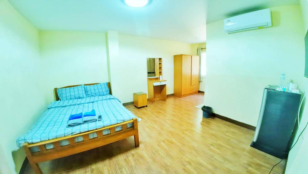 a bedroom with a bed with blue sheets and a wooden floor at เอสดี ดี พี อพาร์ทเม้นต์ in San Kamphaeng