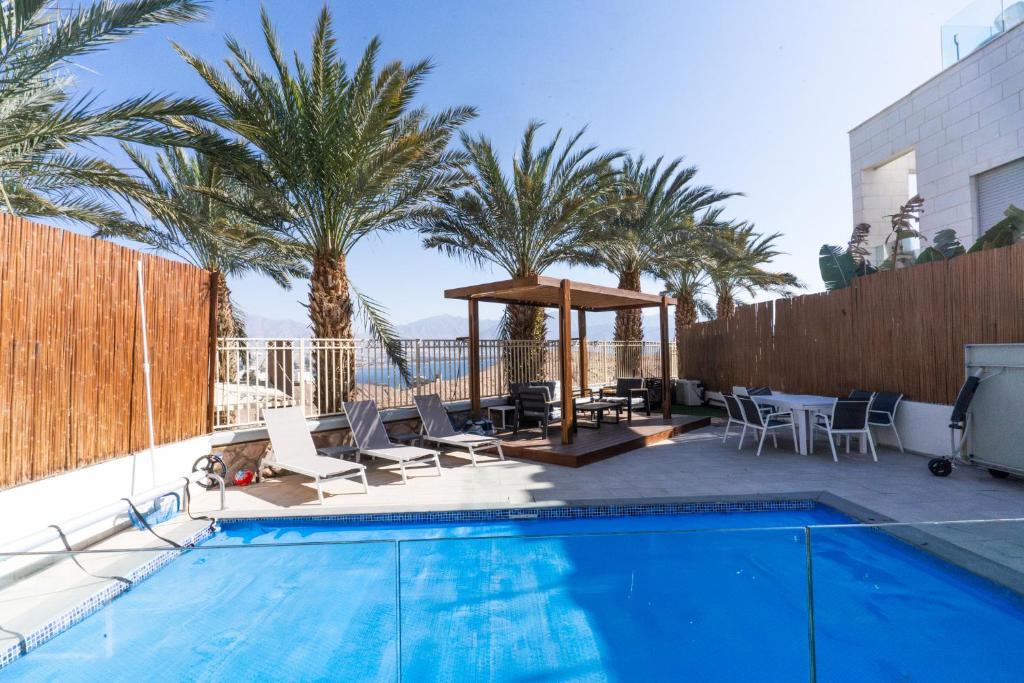 a pool with chairs and a gazebo and palm trees at villalis bay view in Eilat
