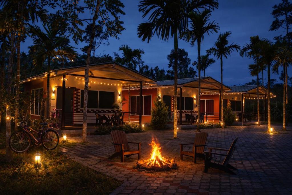 a house with a fire in front of it at night at Rainy Cloud Homestay Private Cottages -Pool, Estate, Near to Falls & Safari in Chikmagalūr