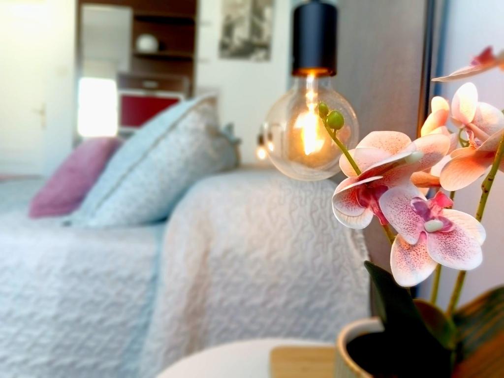 a vase with flowers on a table next to a bed at Villasultana 1 in Chipiona