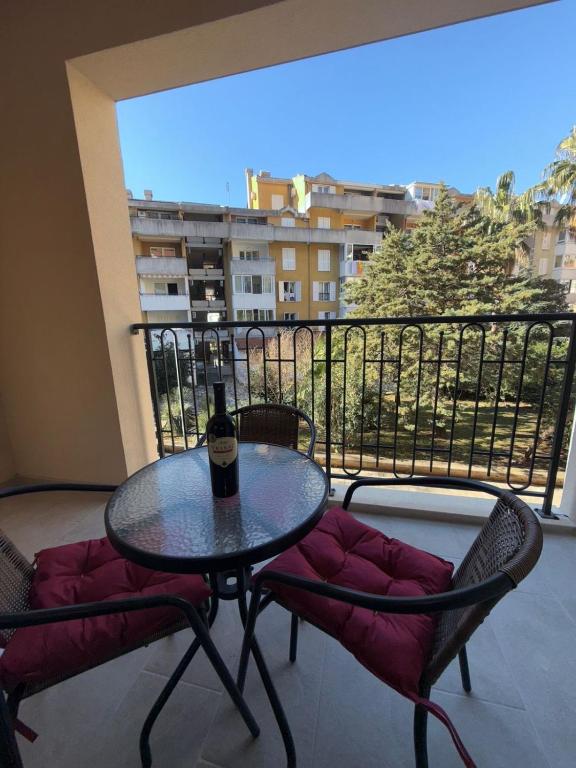 a table and two chairs with a bottle of wine on a balcony at Bozovic Apartman 2 in Budva