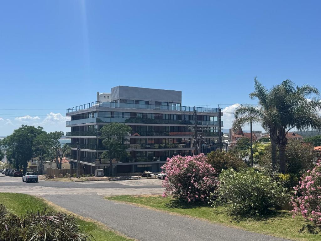 a tall glass building with a road in front of it at Apartamento Piriapolis in Piriápolis