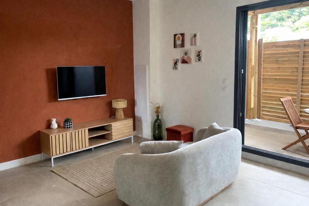 a living room with a tv on a wall at T2 cosy - Ti nid vert in La Possession