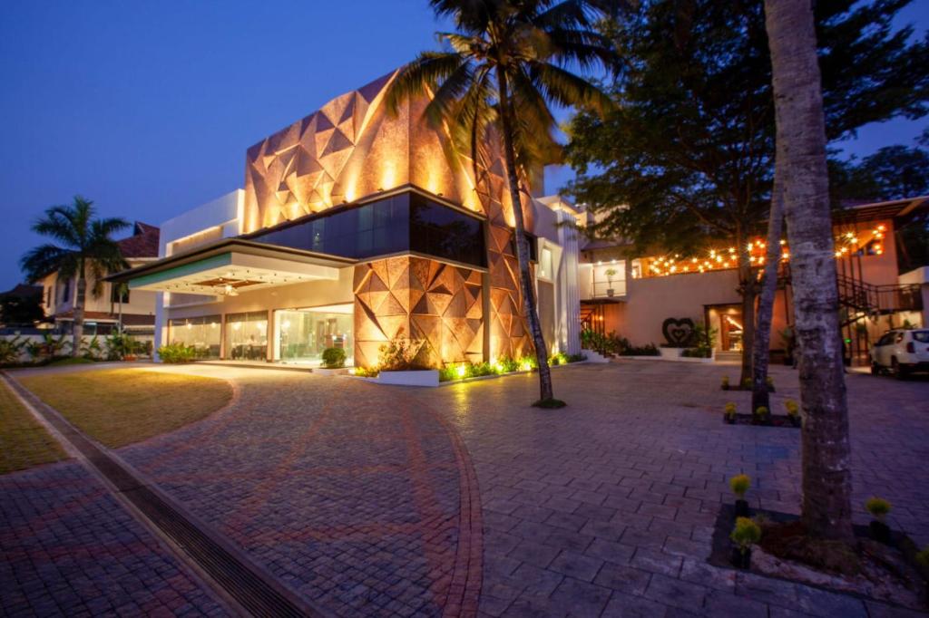 a building with a palm tree in front of it at Hotel Gentleman Plaza in Alleppey