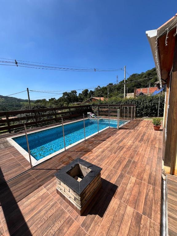 a wooden deck with a fire pit next to a swimming pool at Refúgio Bosques de Itu in Itu