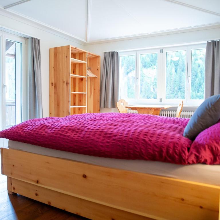 a large bed with a purple comforter in a bedroom at Gasthaus Sonne in Urnerboden