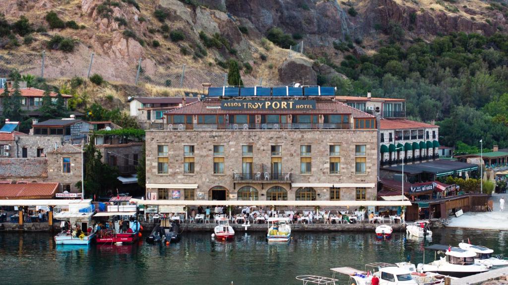 a large building with boats in a body of water at Assos Troy Port Hotel in Behramkale