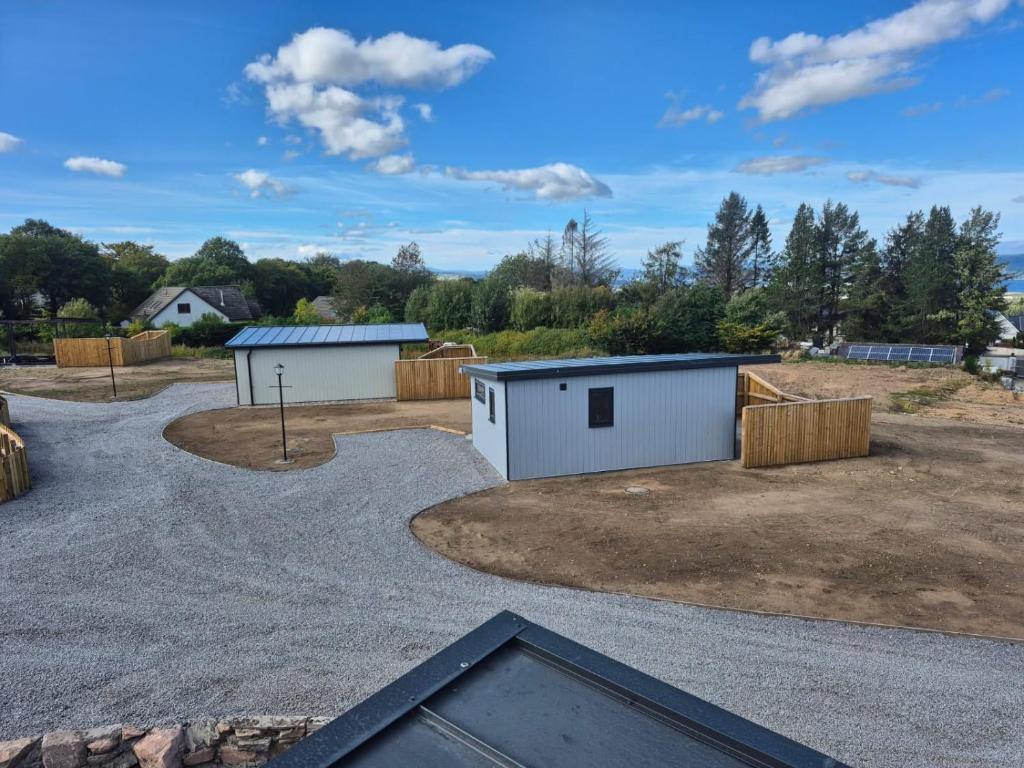 a parking lot with two buildings in a yard at Inverness Ardtower Escapes in Culloden