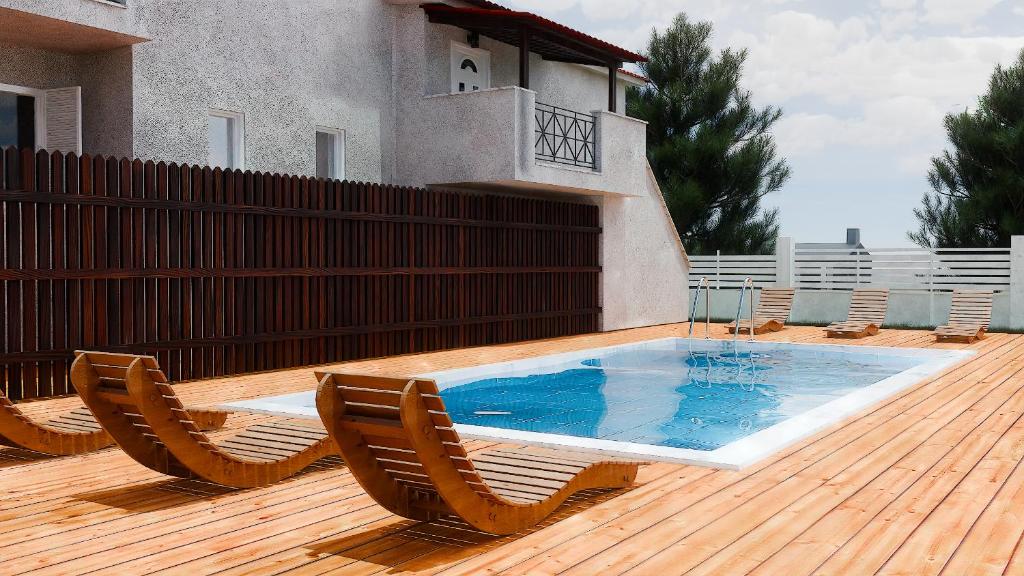 a swimming pool with two chairs and a wooden deck at Ilias Village in Skiathos