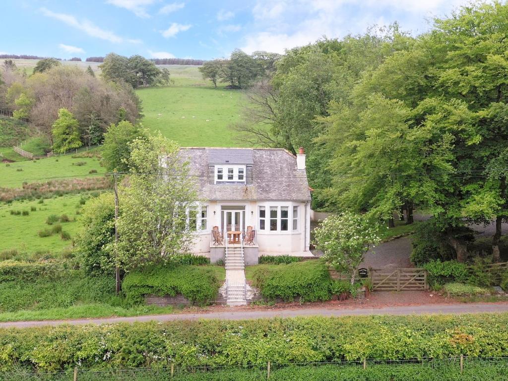 a large white house in a field with trees at Pinclanty Cottage in Pinmore