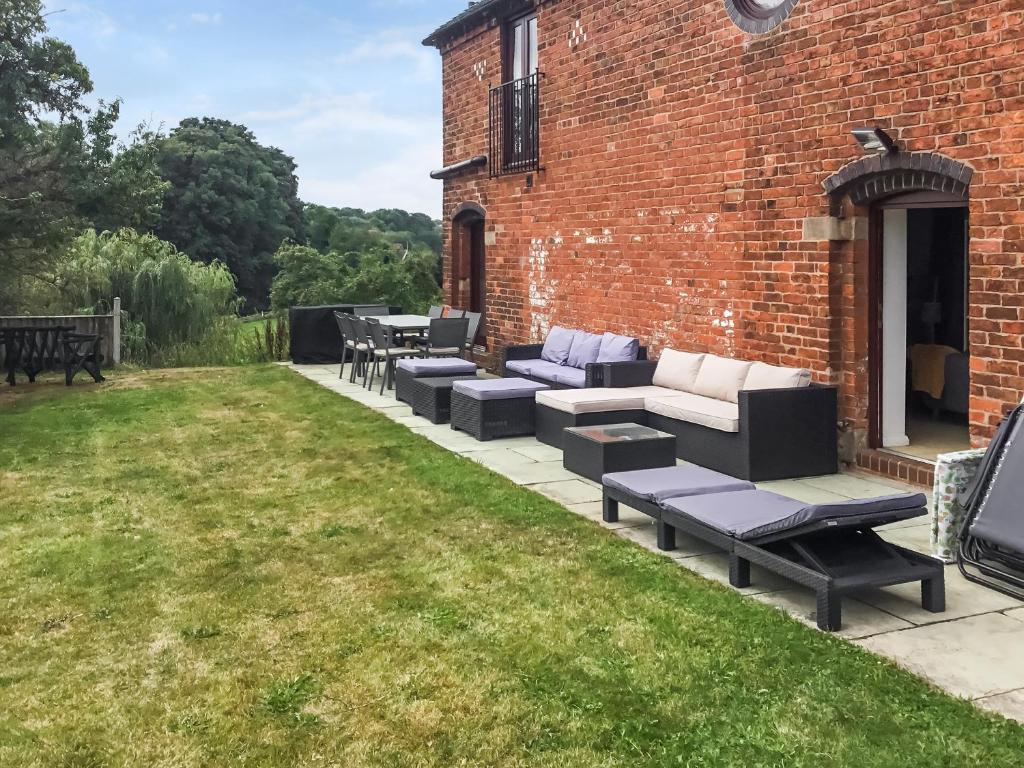 a patio with couches and tables in a yard at Mill House Barn in Warmingham
