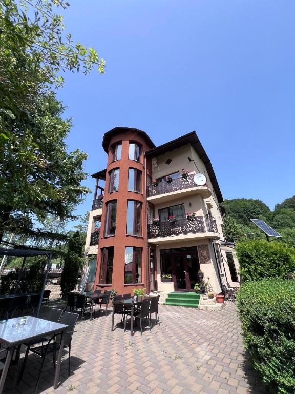 a building with tables and chairs in front of it at Pensiunea Silvian in Cheia