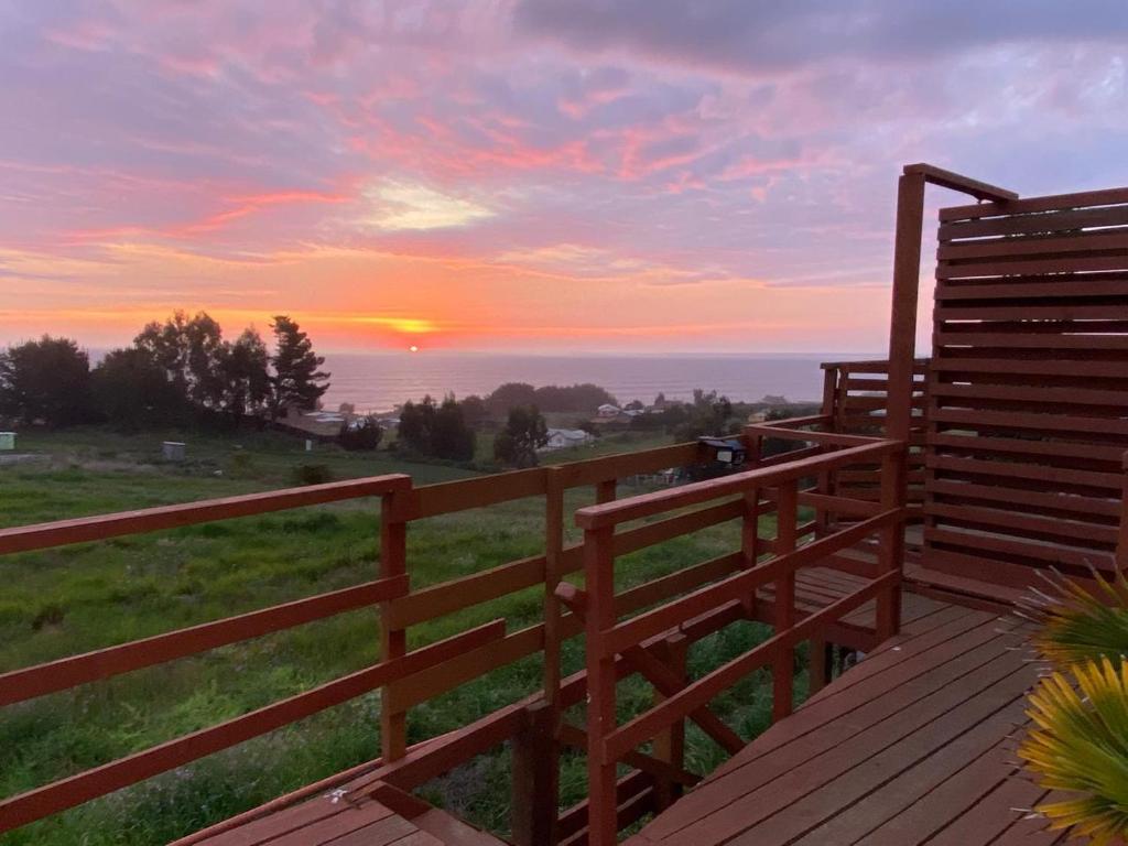 a sunset over the ocean from a wooden deck at Cabañas Bellavista del mar in De Cauquenes
