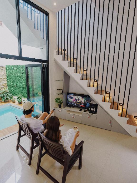 two people sitting in chairs in a living room watching tv at TITANIUM 9 Villa in Tlekung