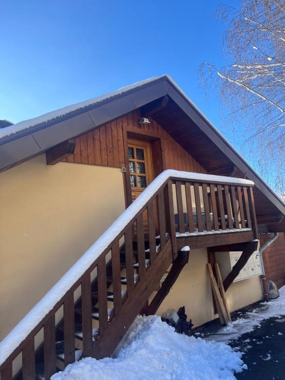 chata z drewnianymi schodami na śniegu w obiekcie Studio chambre w mieście Cruseilles