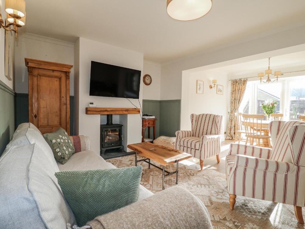 ein Wohnzimmer mit Sofa, Sesseln und Fernseher in der Unterkunft Parkfields Cottage in Uttoxeter