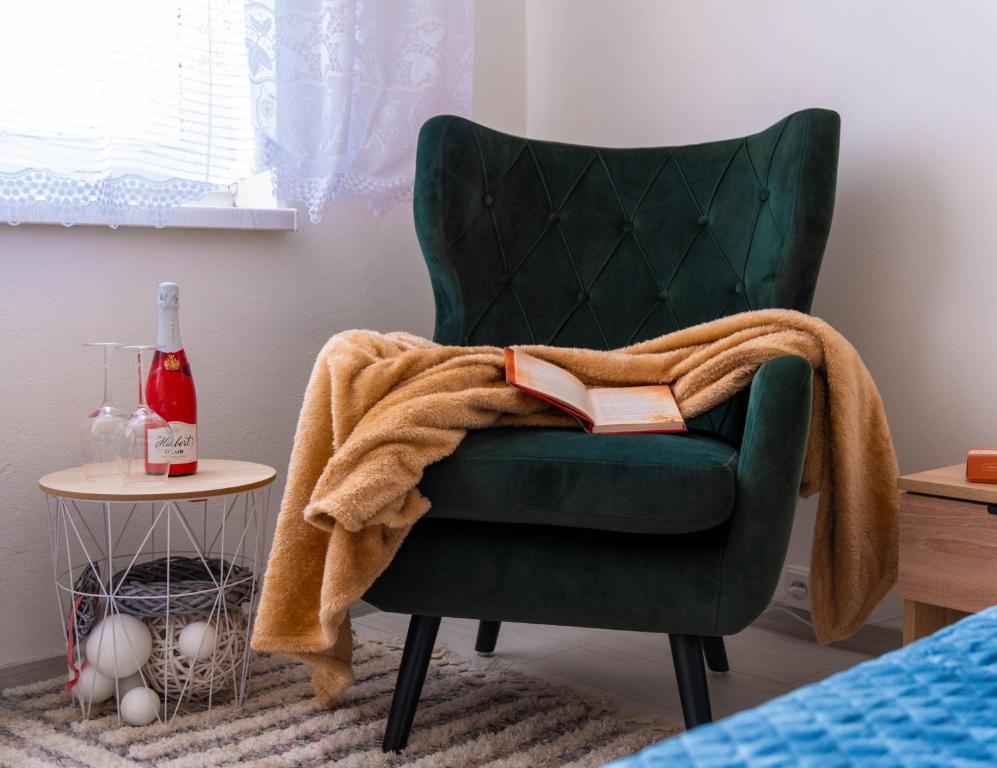 a green chair with a blanket on top of it at LM Apartman in Spišská Nová Ves