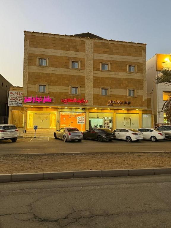 ein Gebäude mit auf einem Parkplatz abgestellten Autos in der Unterkunft فواصل2 in Tabuk