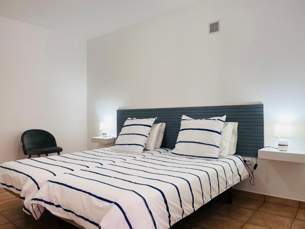 a bedroom with a large bed with striped sheets and pillows at Casa Pão - 5 mins from Machico centre with private parking in Machico