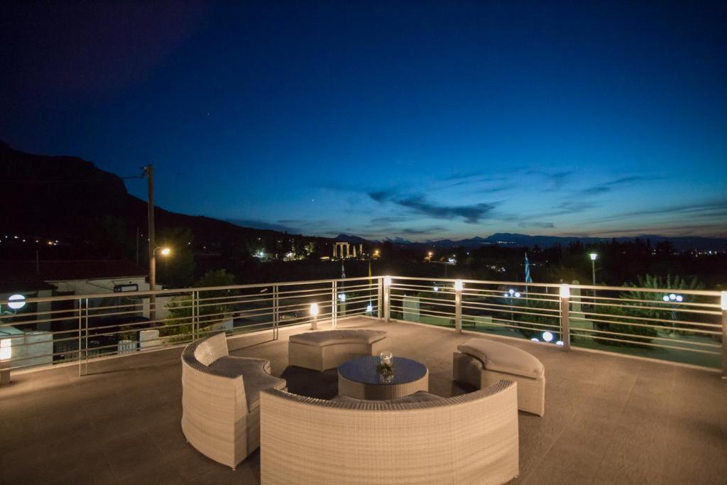a deck with couches and tables on a balcony at night at Apollonio Suites in Korinthos